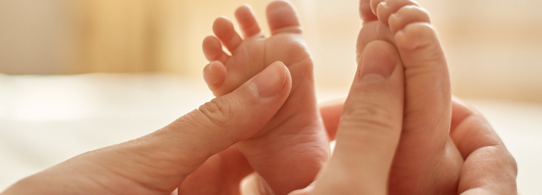 Volwassen handen houden voorzichtig de voetjes van een baby vast.