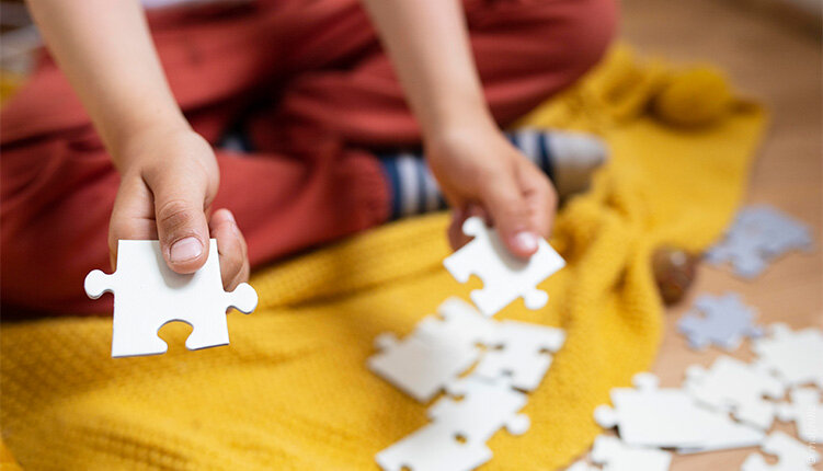 Kind houdt puzzelstukken vast tijdens een spel- of begeleidingsactiviteit
