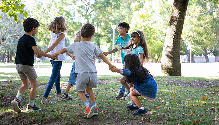 Groep kinderen speelt samen in een groene parkomgeving.
